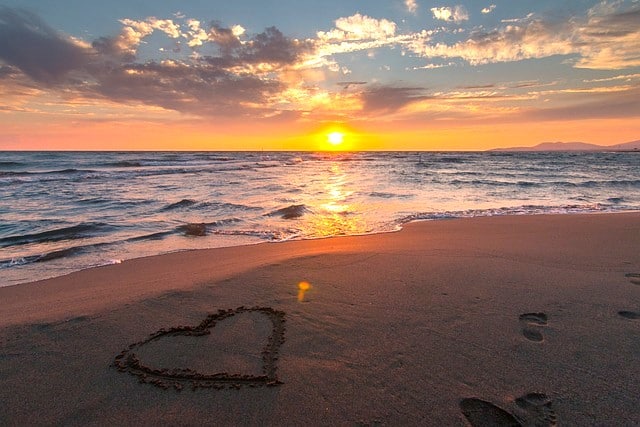 ocean sunset with heart drawn in sand