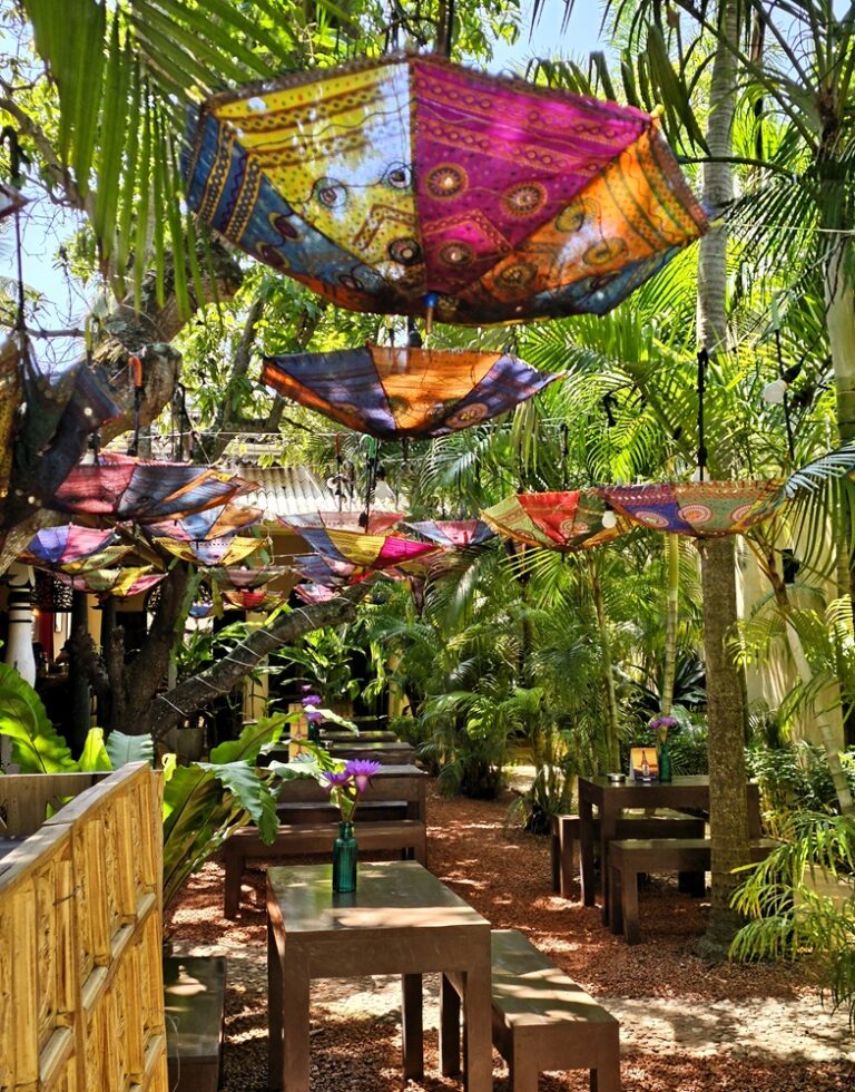 a shaded restaurant with upside down bright umbrellas and lush vegetation - perfect for those with chronic health conditions wanting to escape the heat