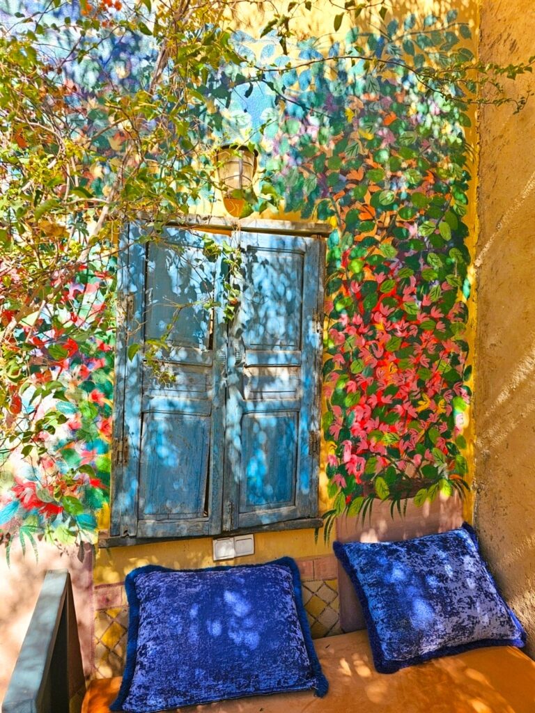 a seating space with lovely flower painted wall at  Dar Tourkia - Taroudant. A perfect space for lounging when you have a health condition. 