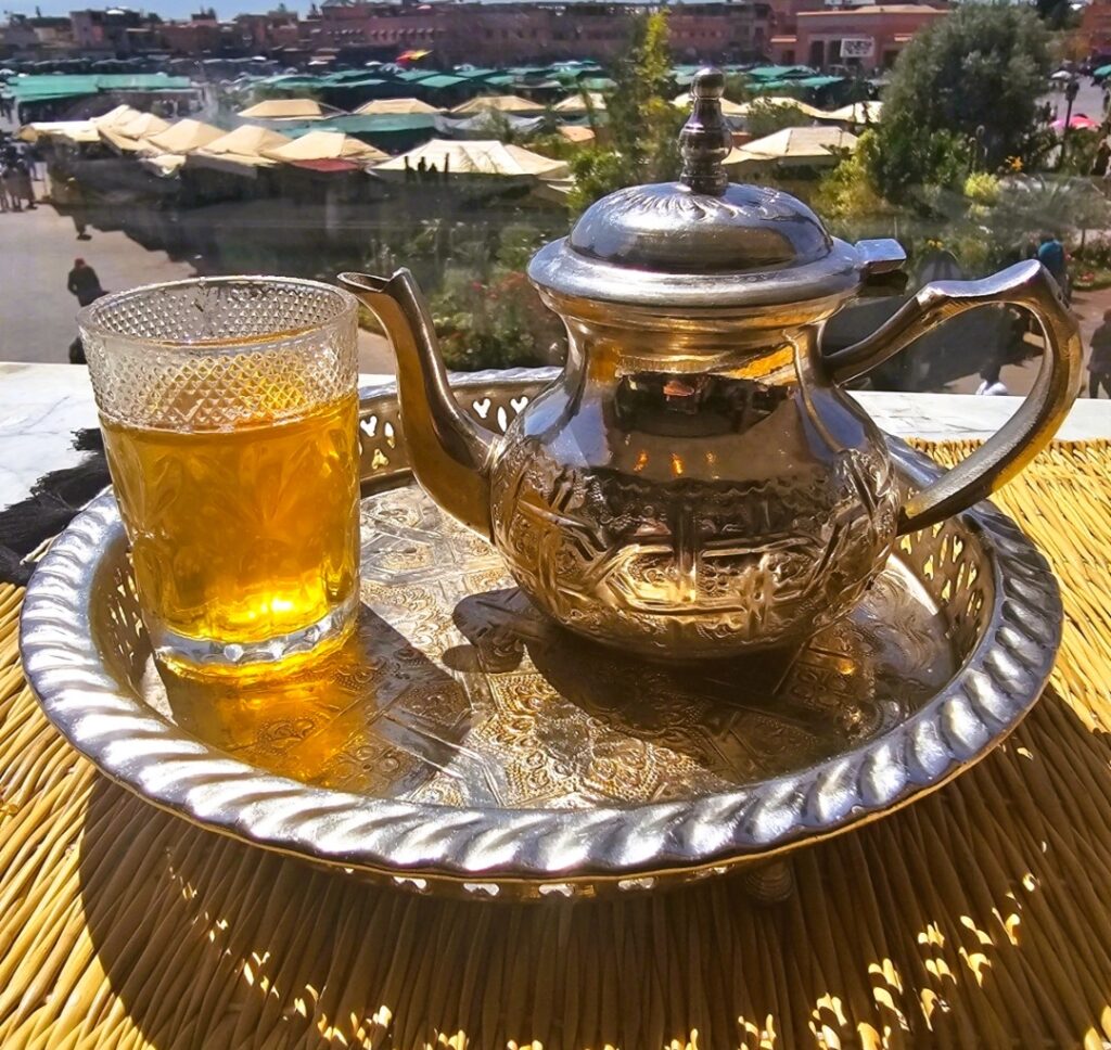 a silver tea pot with a glass of mint tea over looking the main square of Marrakech 