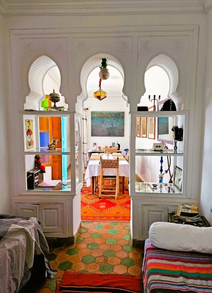 a white room with tiles, bright rug and a table in the distance 