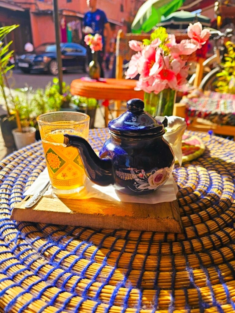 a blue tin tea pot with a class of mint tea on a straw mat - a prefect break for women over 50 with health issues 