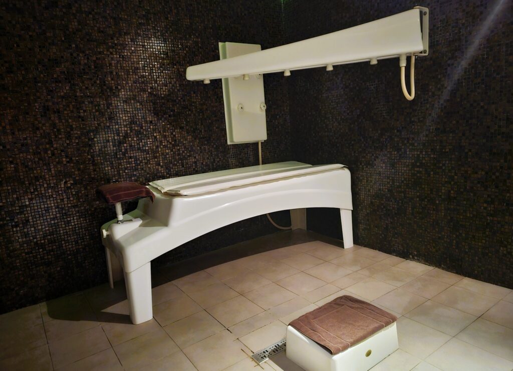 a treatment bed with a shower above it with various jets at Mövenpick Resort & Marine Spa 