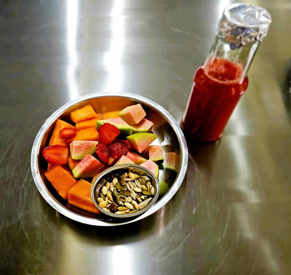 a bowl of fruit and juice for breakfast at   at Nirvana Naturopathy Retreat & Hospital 