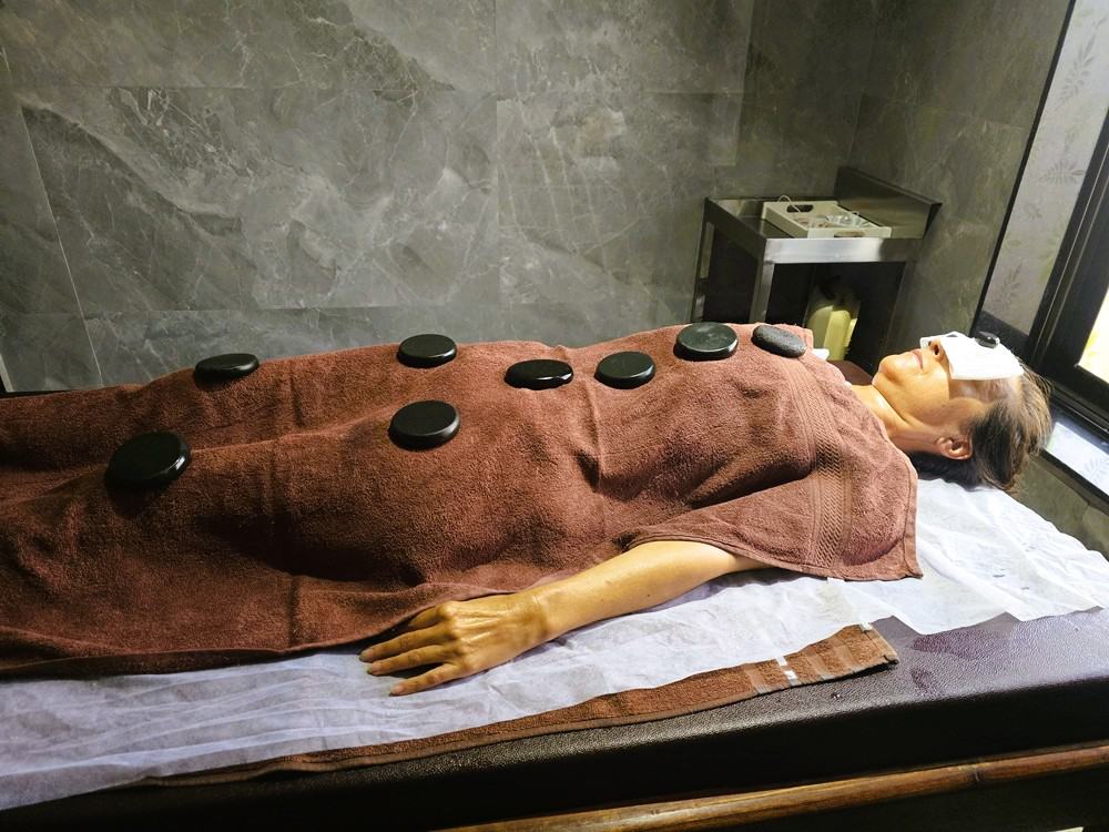 Myself laying down covered with towels and hot stones at  Nirvana Naturopathy 