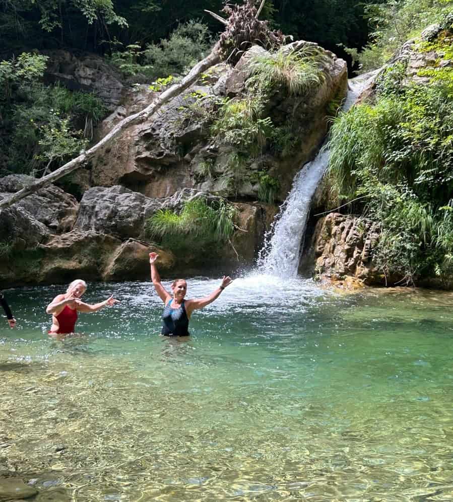 Two women having fun a natural pool at Rosmarino Retreats for Midlife Women in Italy 
