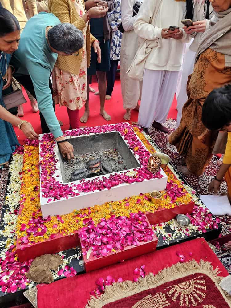 fire ritual - bright pink and yellow flowers with people taking ash from inside