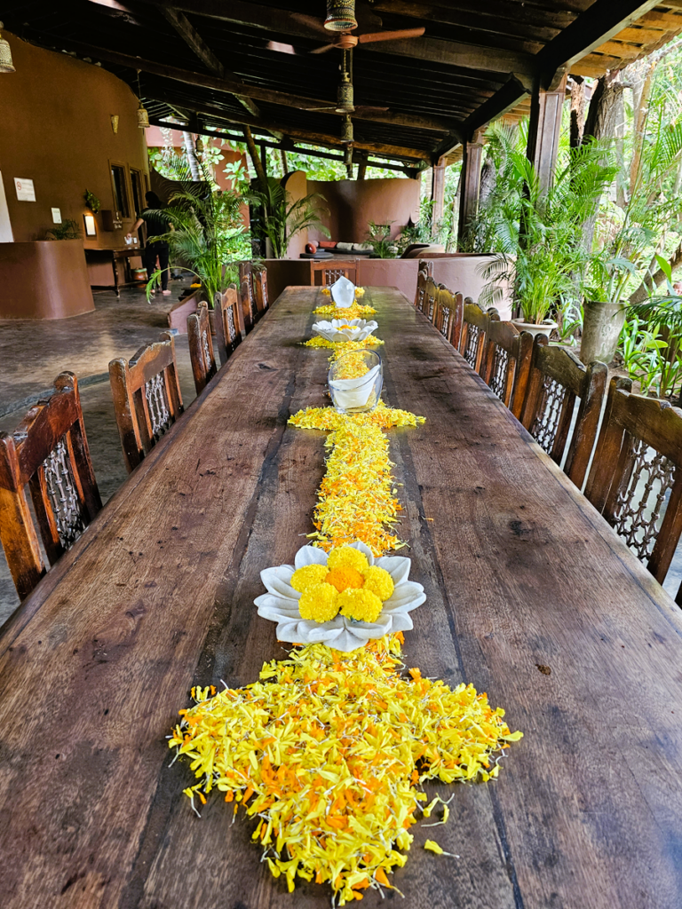 long wooden table with flowers at Ashiyana Yoga Retreat, Goa, India 