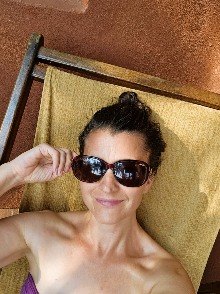 Relaxed woman with sunglasses lying on a sunbed at Ashiyana Yoga Retreat Goa.
