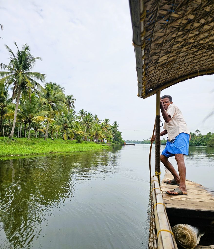 man pushing pole into the water on eco backwaters cruise in Kerala