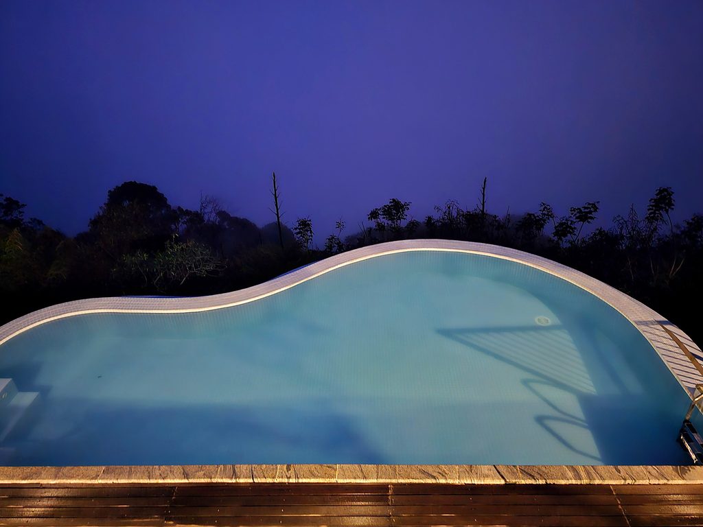 the pool lit up at night at Blackberry Hills Hotel in Munnar