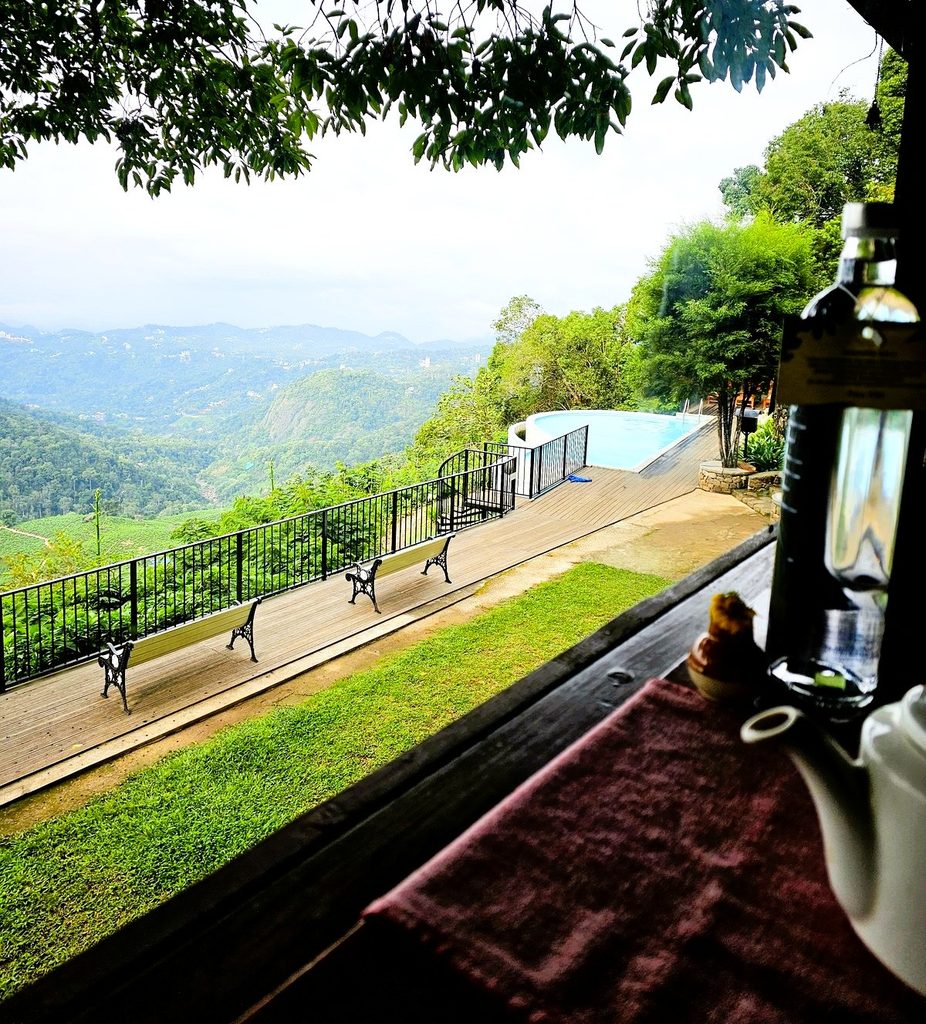 shows the edge of a table with a teapot overlooking the grounds, pool and valley 