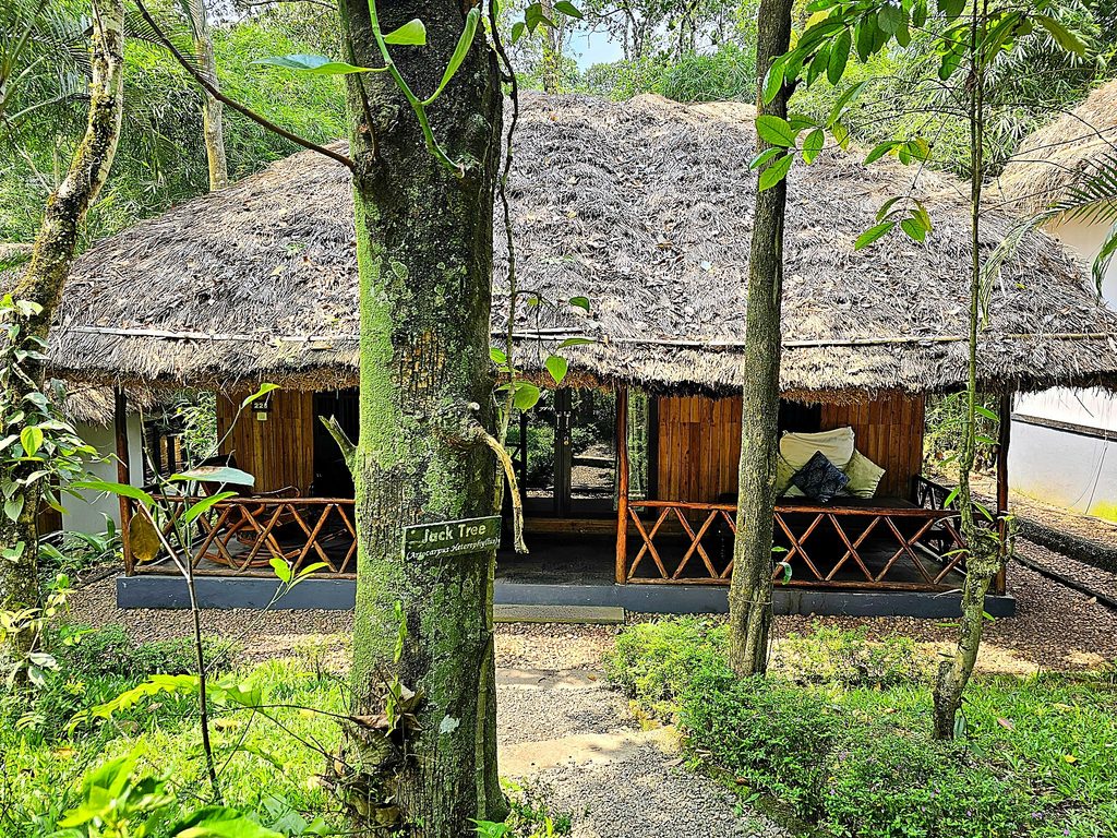 a small cabin with a thatched room and wooden fence at Amritara Shalimar Spice Garden Resort & Spa