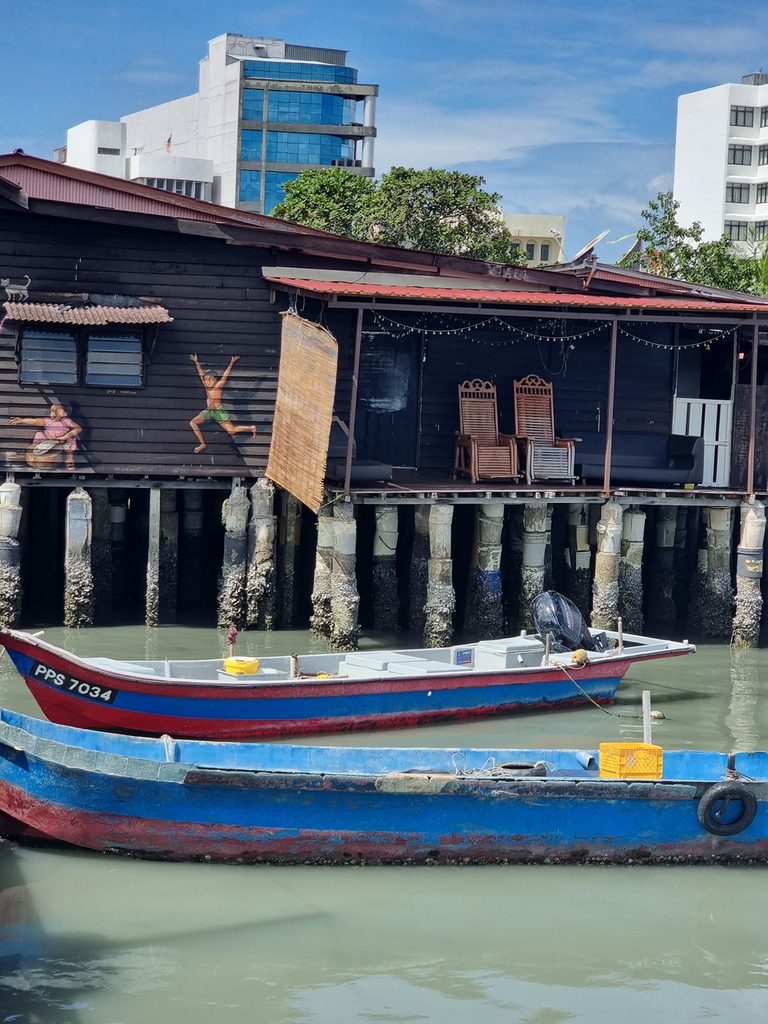 two boats in front of a building with street art on the clan jetties