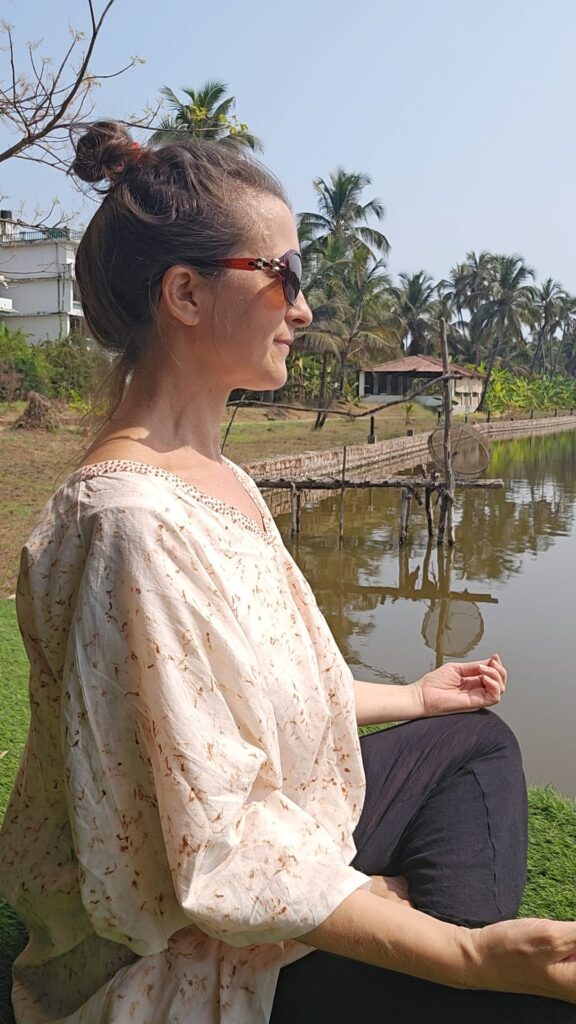 myself sitting cross legged next to the lake at Veda5 Goa 