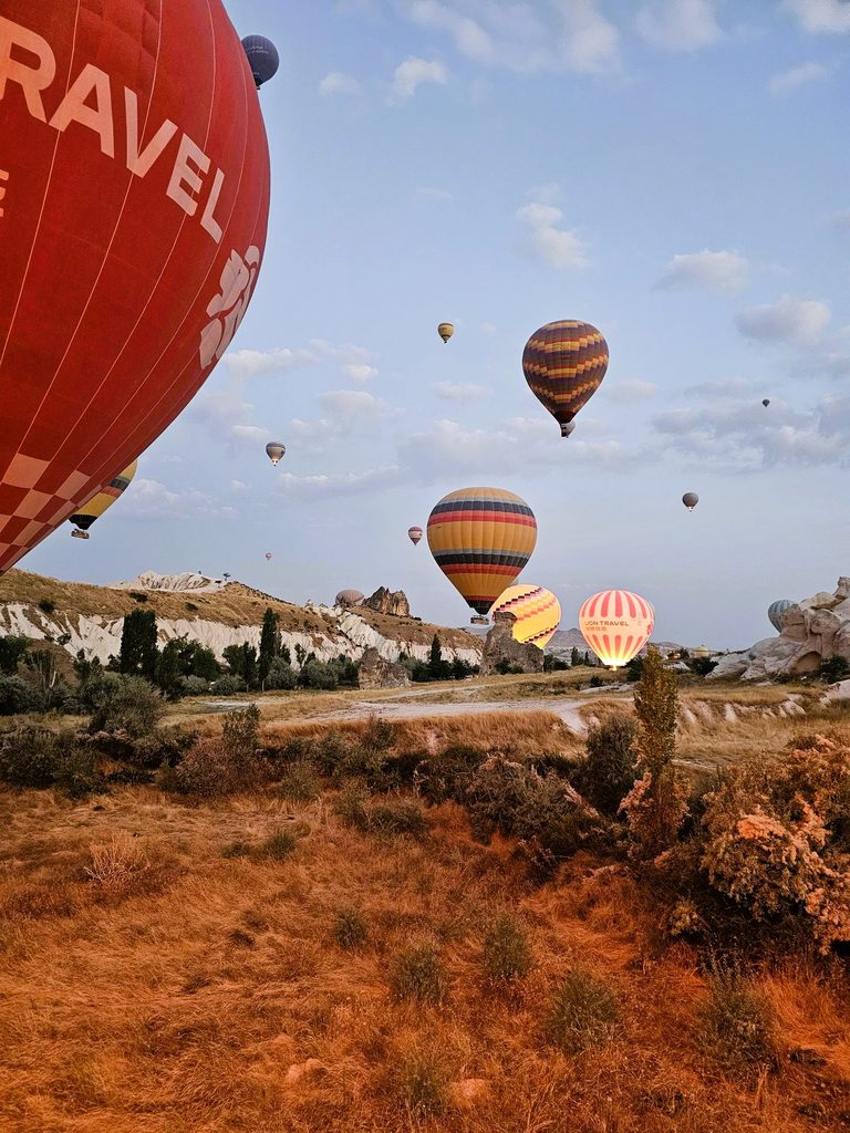 several hot air balloons rising from the ground in Cappadocia