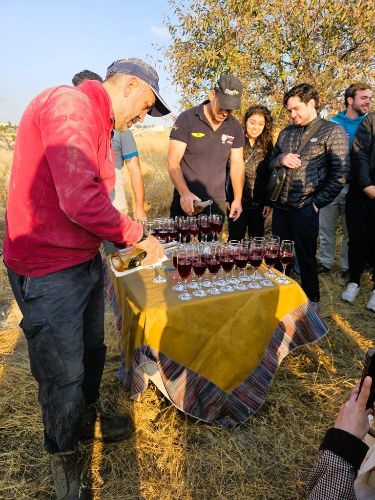 Group of people gathered around a table with drinks being poured by the pilot - red juice