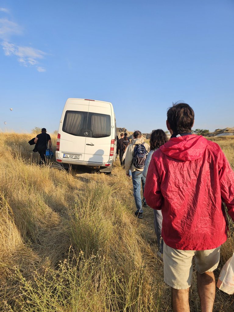 shows the van from behind with a queue of people