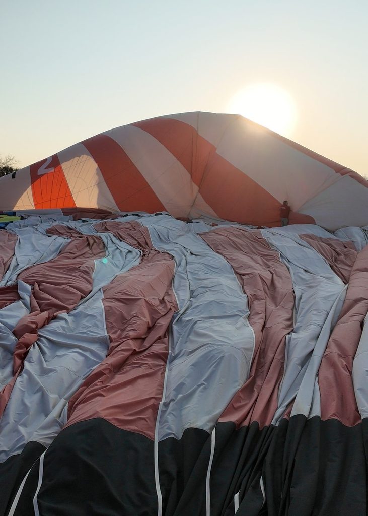 balloon deflating on the ground with the sun in the distance