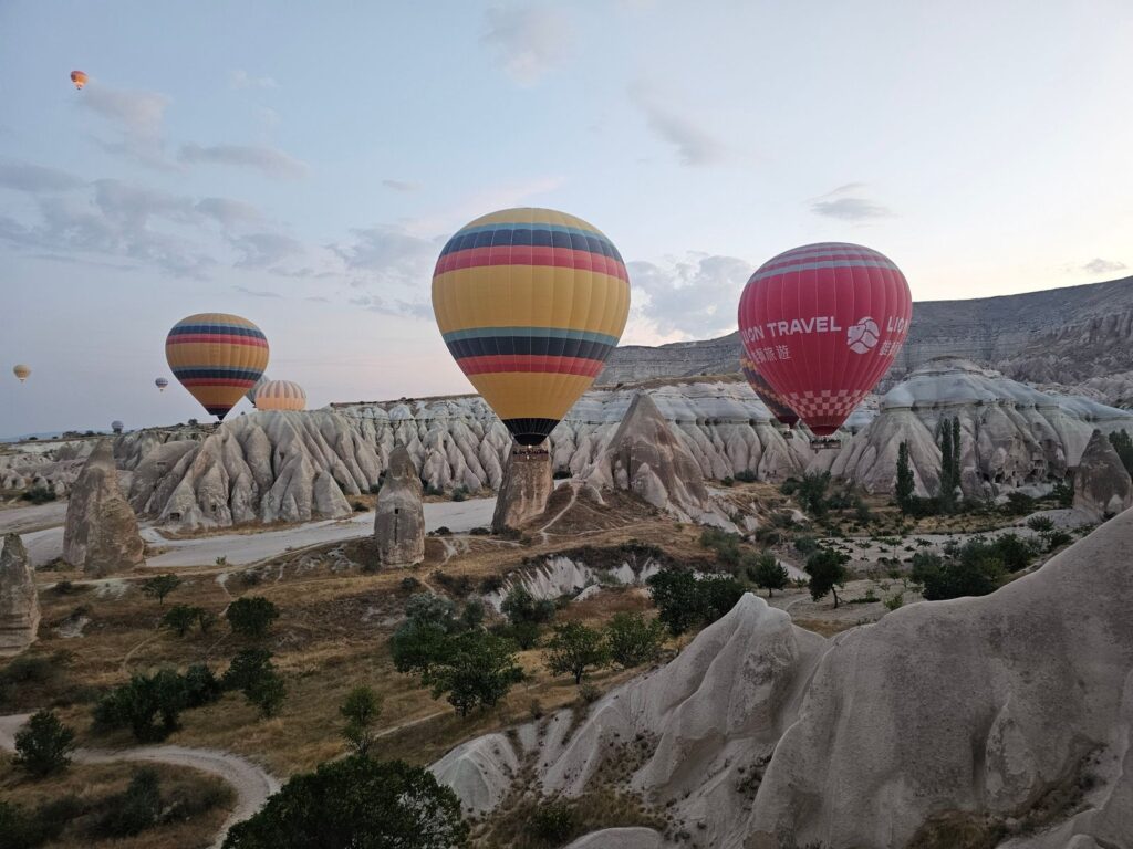 3 large hot air balloons gliding over the rocky surface in Cappadocia