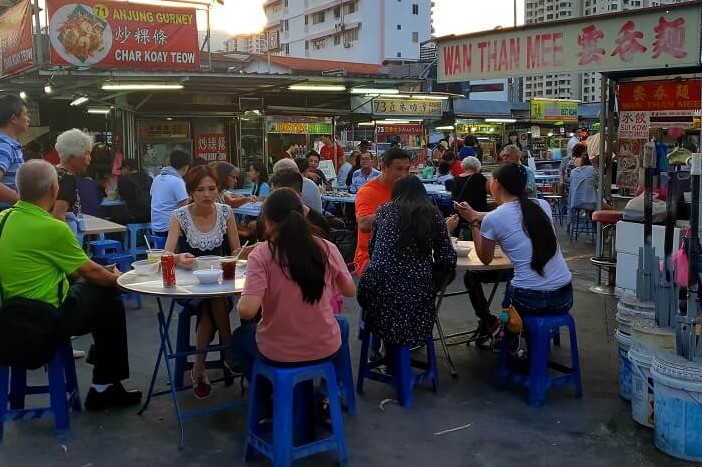 Gurney Drive Hawkers - people sat at a table eating.