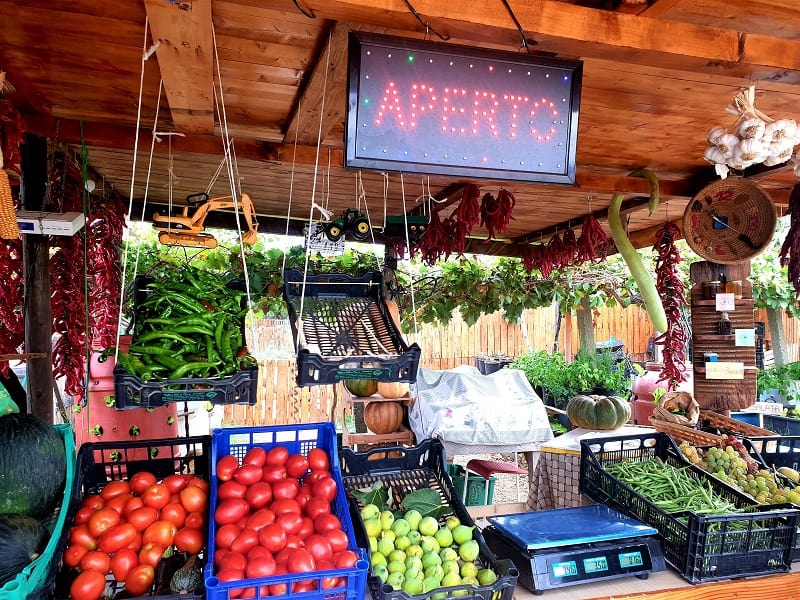 A farm shop stall showing juciy red tomatoes, figs, green peppers and chillis 