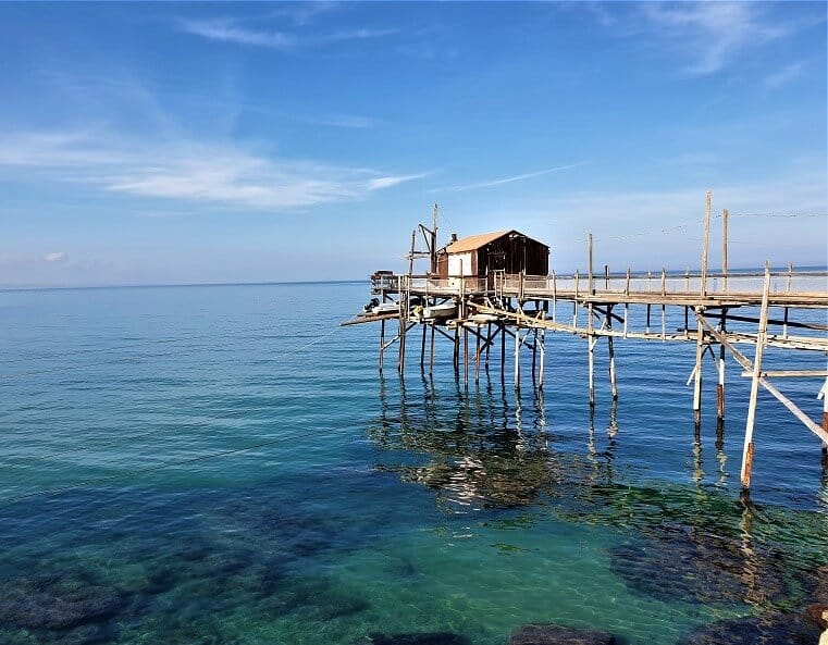 A traditional fishing platform on a sunny day. The ocean is calm, blue and clear.