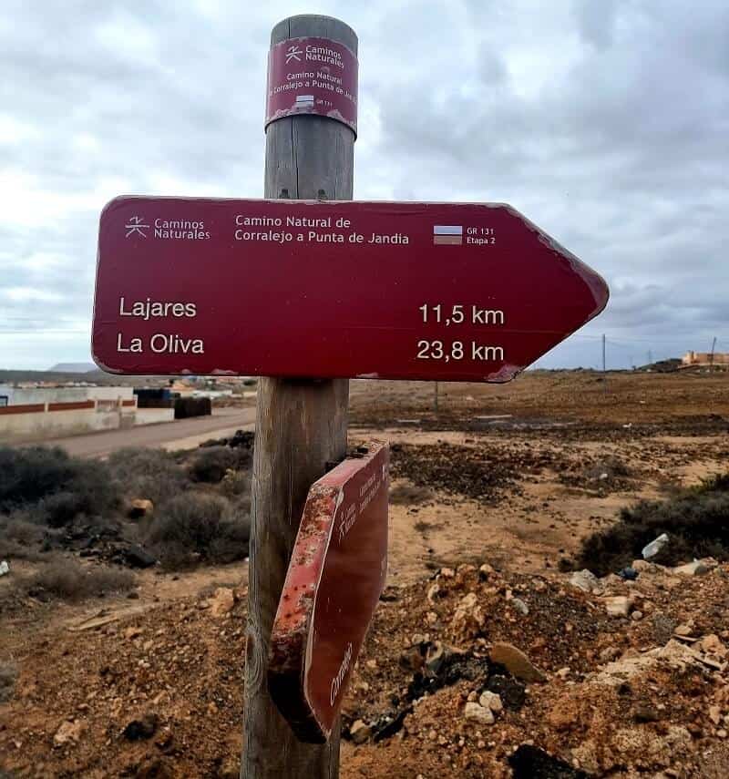 A sign post stating Lajares 11.5 km and La Oliva 23.8 km