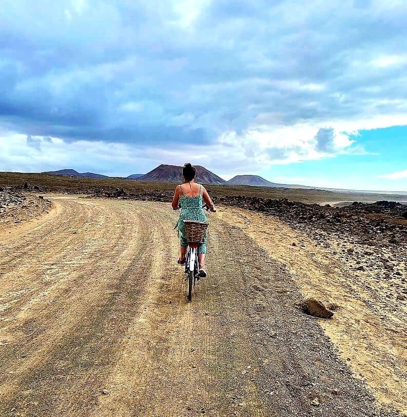 Cycling into the distance amid rocky landscape on a hybrid ladies bike with a basket on the back