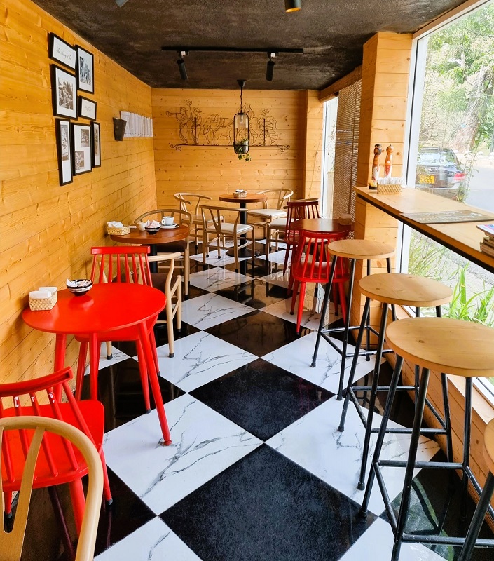 Interior of Cafe Kandyana, black and white checked floor, red tables and wooden walls, black and white pictures