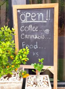 A cafe board showing Open, coffee, cannabis, food 