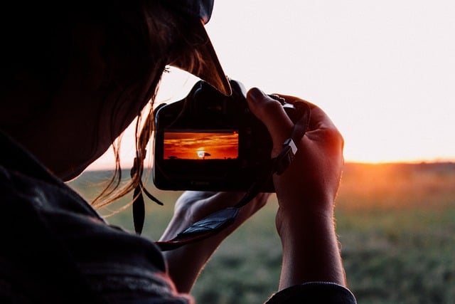 A women looking through the viewfinder of a camera at a sunset